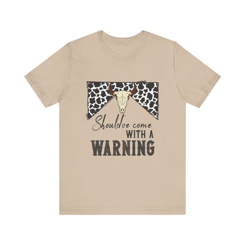 hope + joy collective tan short sleeve t-shirt with a graphic image of a leopard banner and cow skull in the middle that says "Should've Come with a Warning" in western font