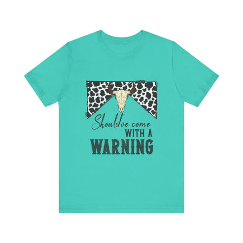 hope + joy collective teal short sleeve t-shirt with a graphic image of a leopard banner and cow skull in the middle that says "Should've Come with a Warning" in western font