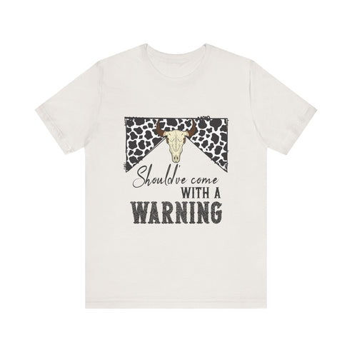 hope + joy collective heather vintage white short sleeve t-shirt with a graphic image of a leopard banner and cow skull in the middle that says "Should've Come with a Warning" in western font