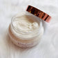 hope + joy collective HJC Luxury Body Cream on white fur in a clear jar with rose gold metallic lid leading off to side to see cream contents