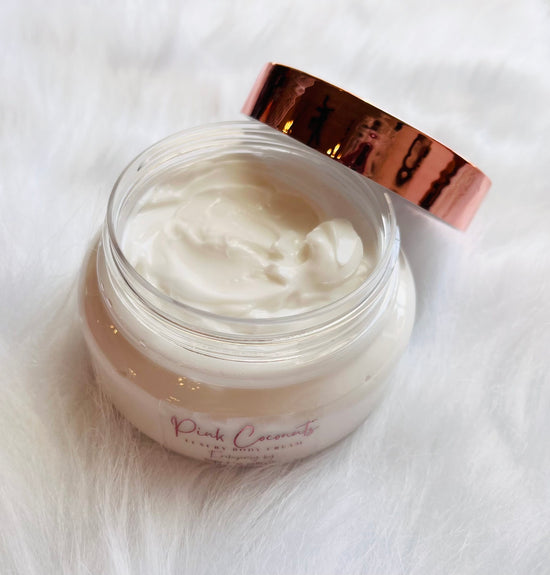 hope + joy collective HJC Luxury Body Cream on white fur in a clear jar with rose gold metallic lid leading off to side to see cream contents