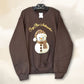 hope + joy collective Cozy Chic Ambassador Snowman Crewneck brown sweatshirt with realistic knit-look image of snowman wearing and leopard print hat and scarf and "Cozy Chic Ambassador" in swirly puff textured font arching over the snowman.