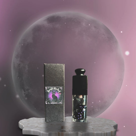 hope and joy collective video of  Moonlit Mischief Lip Gloss tube, black cap and 3D cat on front with rhinestone eyes and labeled box packaging standing on a gray irregular shaped marble stand with a glowing moon in the background and a dark and light purple moving sky with glistening starts.